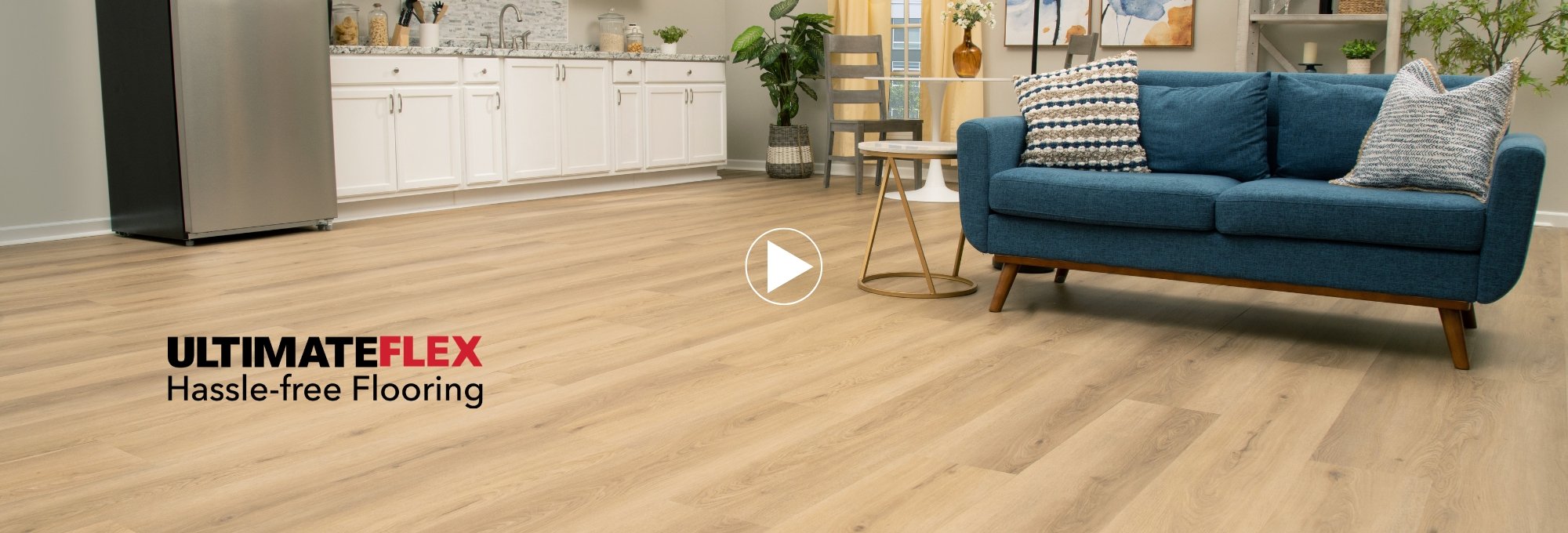 UltimateFlex promotion featuring a studio apartment with a small kitchen and blue sofa on vinyl flooring